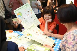 Dr Amy Khor, Senior Minister of State for Health, showcasing the The Recipe for Healthy Ageing poster to a participant.