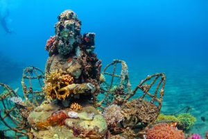 A coral covered Buddha statue rests at the bottom of the sea off the coast of Pemuteran, Indonesia. © Tropical studio / Shutterstock