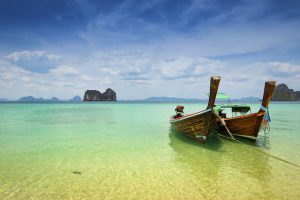 Two wooden longtail boats mooring on the beach with limestone rock formation in the background, Trang, South of Thailand. © Sunphol Sorakul / Getty Images